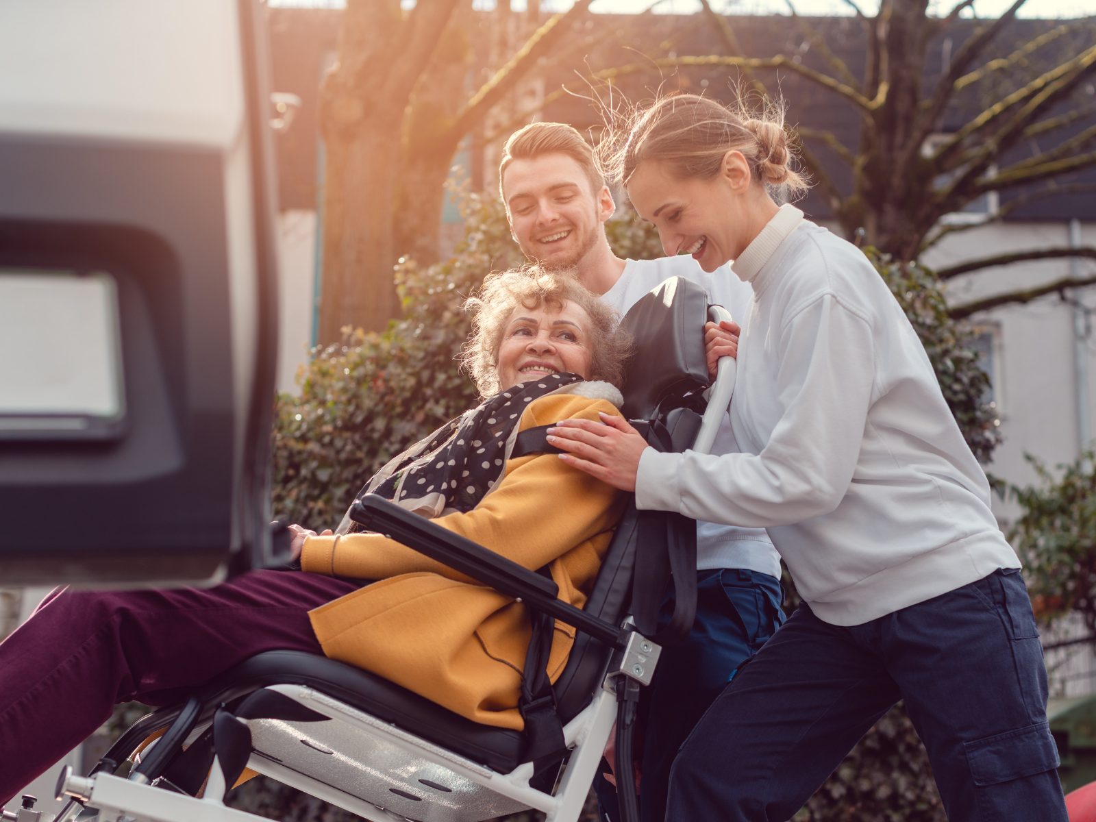 A support worker helping a client into a car for a medical appointment